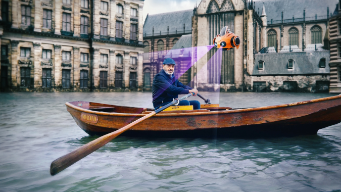 Man in een bootje in een overstroomde stad, met een drone die met hem mee vliegt.